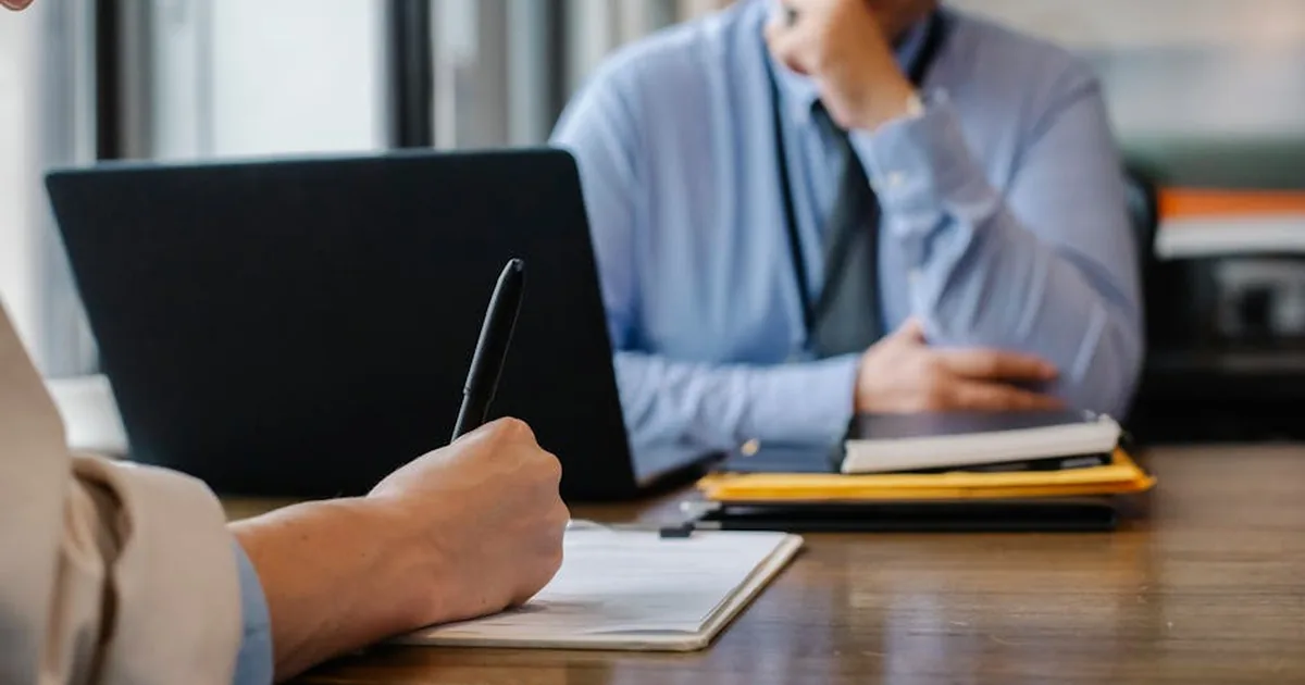 Mão segurando lupa sobre contrato de plano de saúde coletivo empresarial com selo de auditoria jurídica