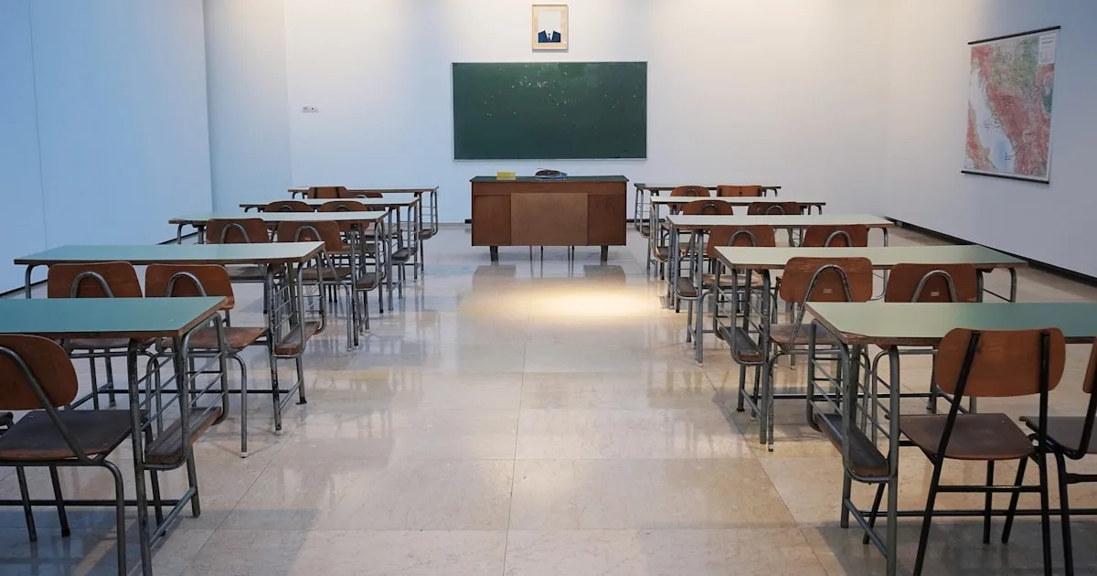 Sala de aula vazia com cadeiras e quadro, representando o ambiente escolar e os desafios de saúde mental na educação