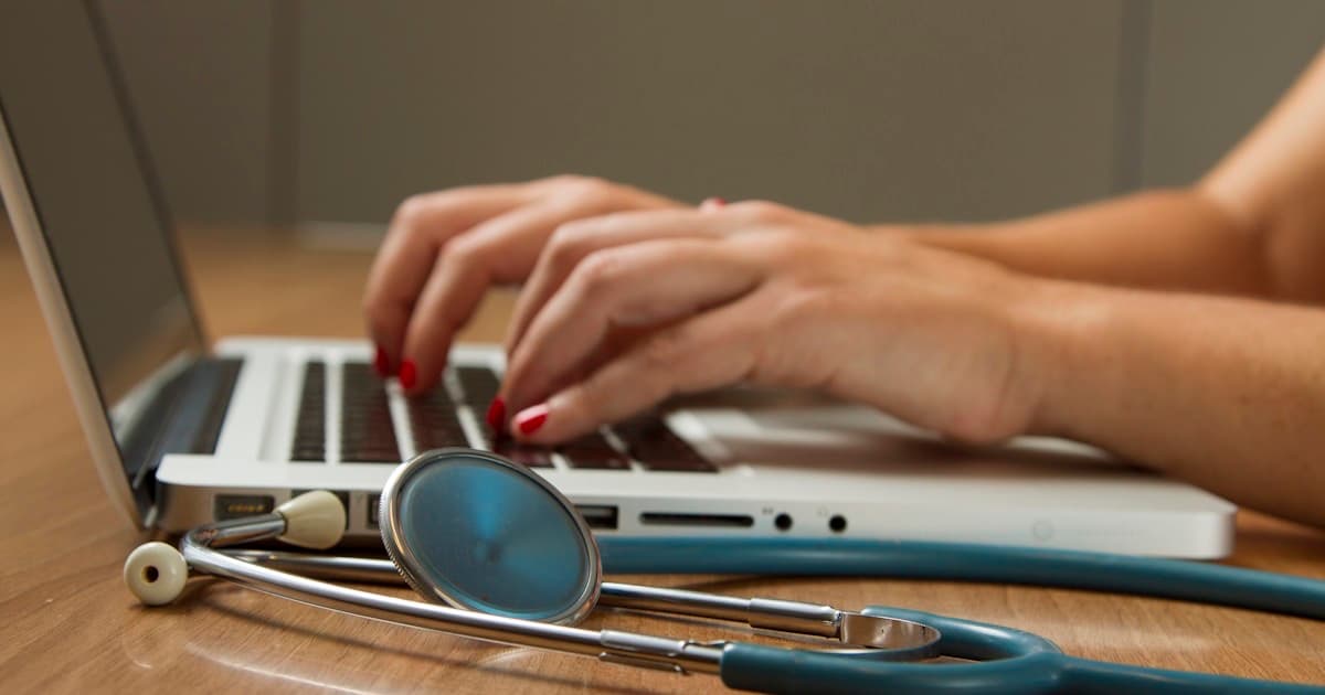 Médico do trabalho analisando dados do PCMSO em tela com indicadores de saúde ocupacional