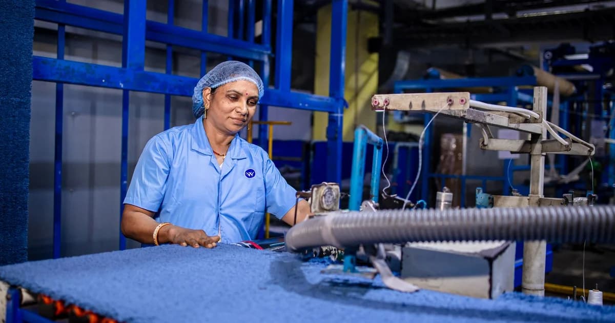 Trabalhadora operando máquina com braço articulado em posto de trabalho industrial