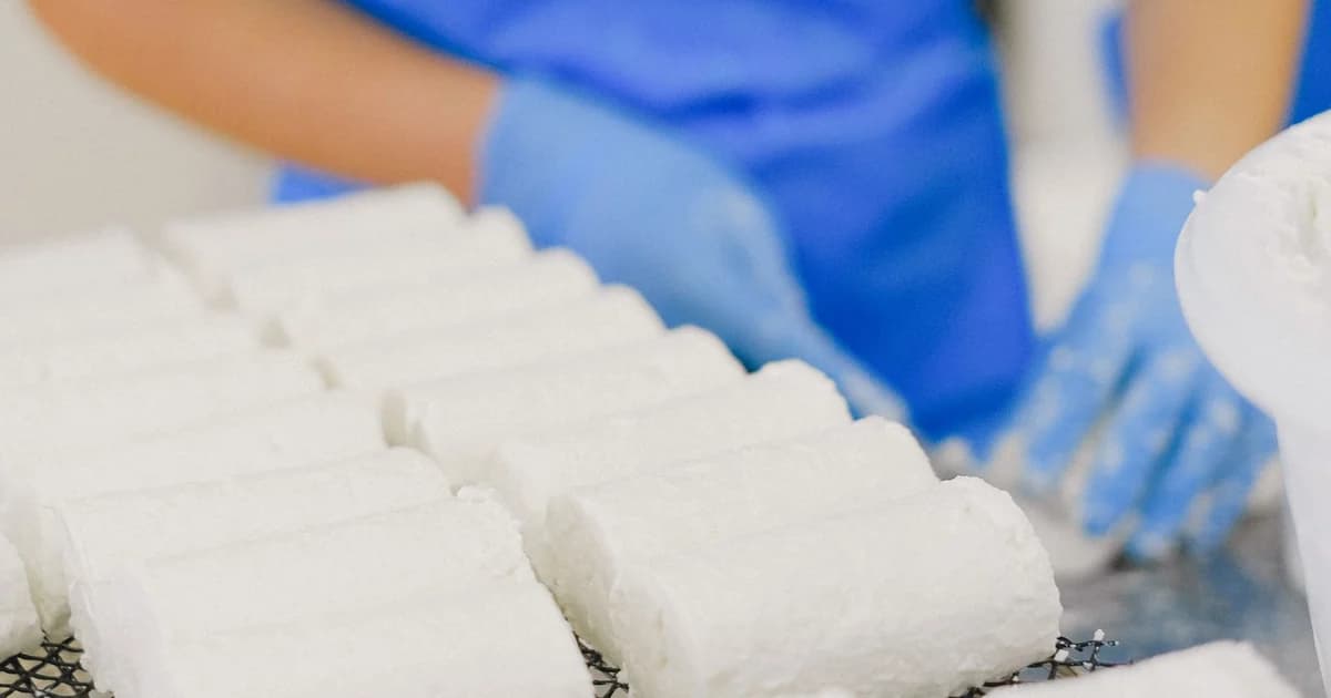 Mãos com luvas de proteção manuseando material em linha de produção industrial