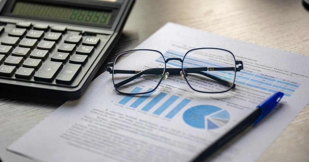 Calculadora e óculos sobre relatório com gráfico